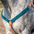 Turquoise-black mohair breastcollar on a gray horse, seen at the chest. The 2-inch mohair strands join a tan leather center piece with a ring, and one side runs up to a ring and tug strap at the saddle.