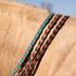 Turquoise latigo laced barrel rein on the neck of a palomino horse, next to chocolate and black laced reins. Turquoise lacing runs through the 5/8-inch harness leather rein.