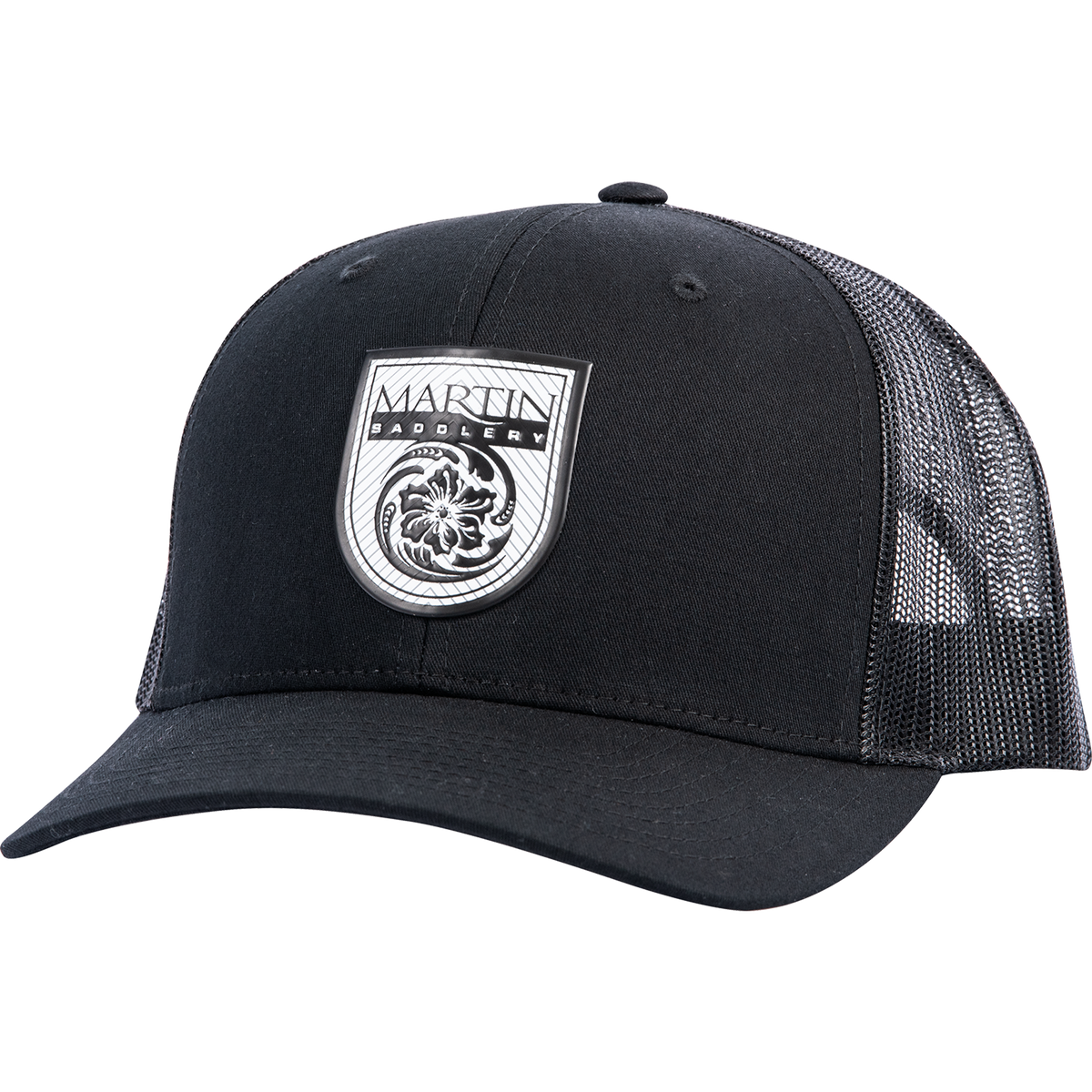 Black trucker cap seen from the front at a slight angle. A white shield logo patch reading Martin Saddlery sits on the front panels, with a precurved bill and a black mesh back.