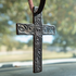 Black tooled leather cross air freshener hanging over a dashboard from a leather tie. Scroll tooling stands out across the arms and length of the cross.