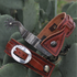 Chestnut square sliding spur straps on a pair of spurs resting on prickly pear pads. The border stamped straps wrap the spur ends, with the buckle on the sliding strap in front.