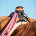 Bungee rope strap from Martin Saddlery holding a coiled pink rope against a saddle horn wrapped in rubber. The black bungee loops over the rope and ties off with a leather latigo.