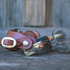 Chestnut smoothout Alpine spur straps on a pair of engraved spurs sitting on weathered boards. The smooth leather straps loop over the spurs with a wide buckle in front.