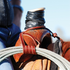 Leather rope strap with a button knot holding a coiled rope below a wrapped saddle horn. The latigo strap wraps the coils and hooks over the horn, with the button knot at the swell.