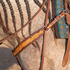 Natural breastcollar strap with floral scroll tooling on a gray horse's shoulder, below a braided mane. The chocolate-framed strap connects to a ring and a buckled tug strap at the saddle on this Martin Saddlery breastcollar.
