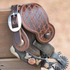 Weathered antique Tombstone spur strap with Twisted Wire tooling on a spur hooked over a wood rail. The tooled strap hangs beside its cart buckle above the engraved spur.