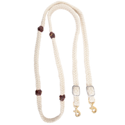 White blended mohair barrel rein, coiled and seen from above. The braided mohair rein has dark latigo leather knots along both sides and ends in buckles with snaps, made by Martin Saddlery for barrel racing.