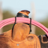 Coiled pink rope held across the swell of a roughout saddle by a black bungee rope strap, seen from the front. The bungee loops run down each side of the swell.