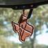 Brown leather air freshener shaped like Texas, hanging from a rearview mirror by a leather tie. The stamped Texas flag design with its star catches the light.