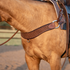 Western breast collar in chocolate leather with quilted tooling on a buckskin horse, seen from the side. The wide steer roper strap sits across the chest and connects to the saddle through a ring and buckled tug straps.